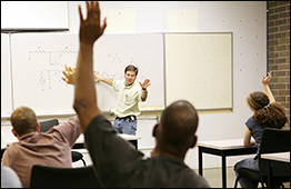 Attendees raise their hands in a classroom setting